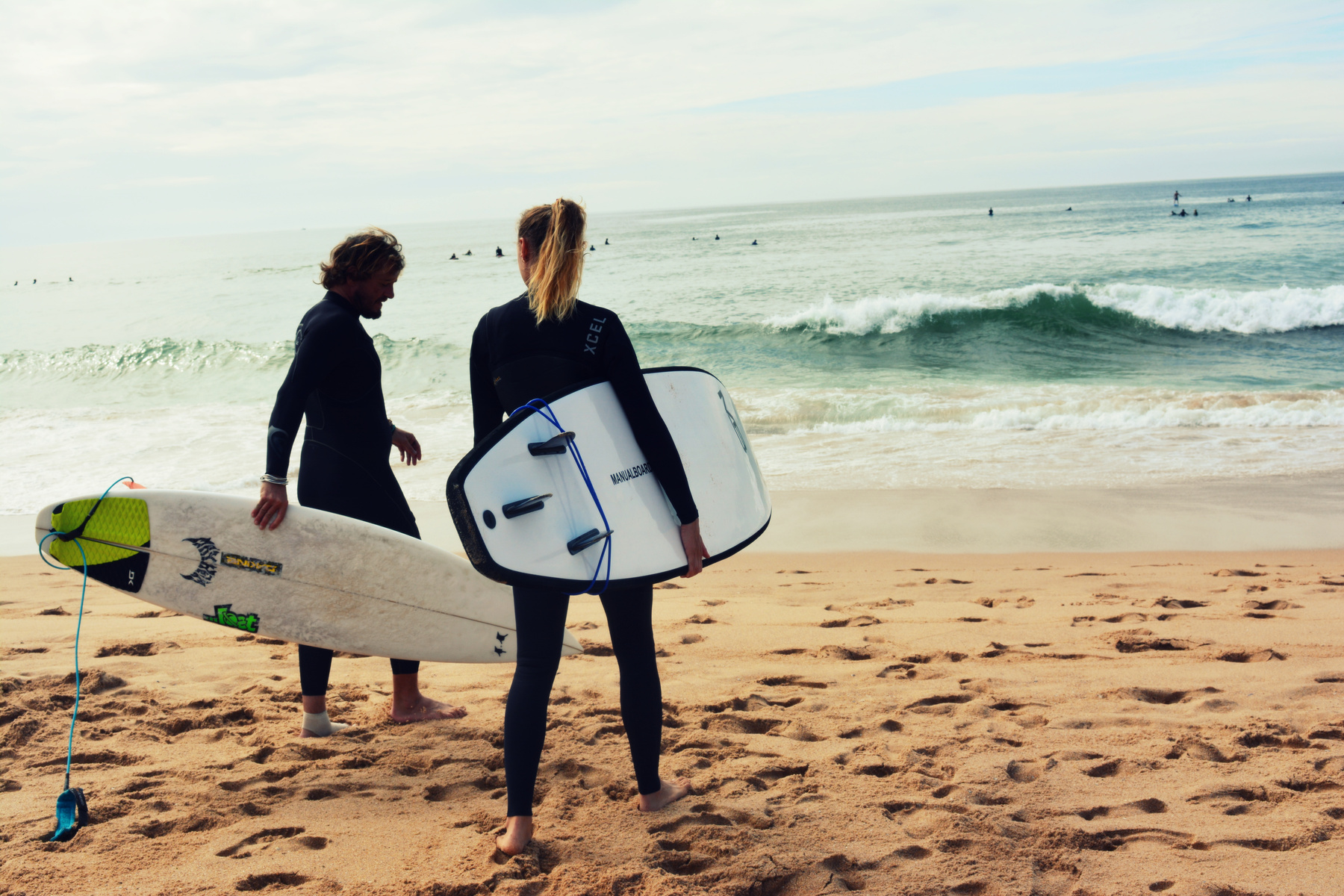 Man and Woman Holding Surfboards on Seashore